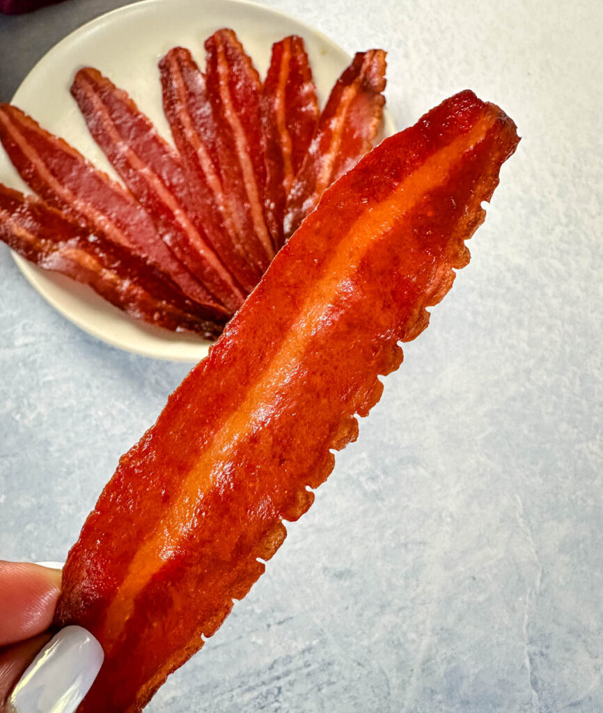 person holding slice of baked turkey bacon