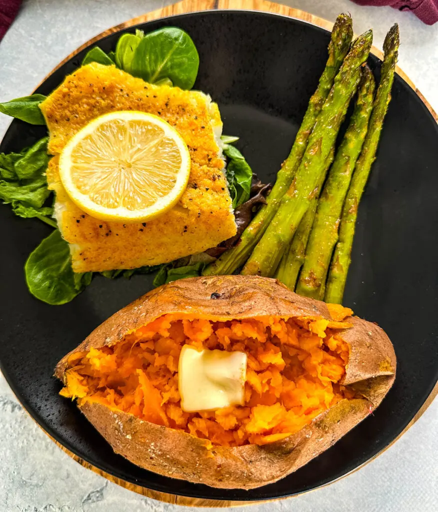 smoked cod, smoked sweet potato, and asparagus on a black plate