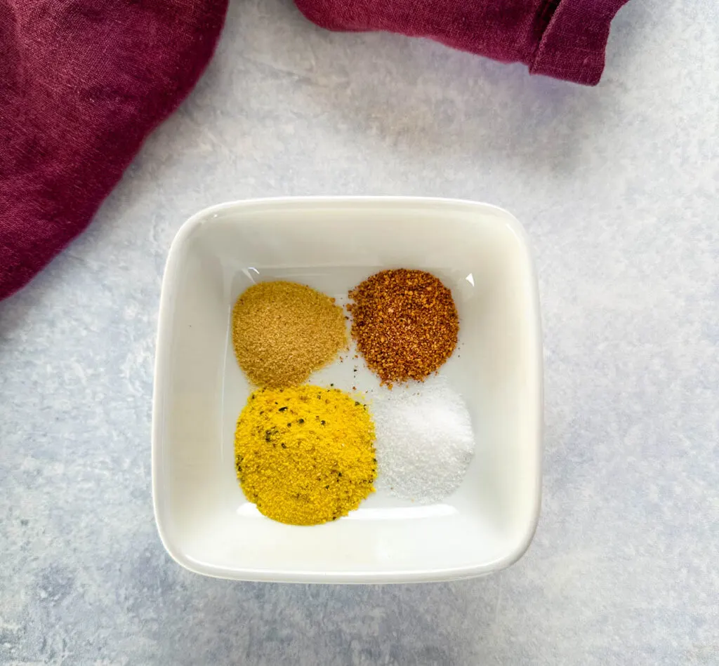 BBQ rub, lemon pepper, garlic powder, and salt in a white bowl
