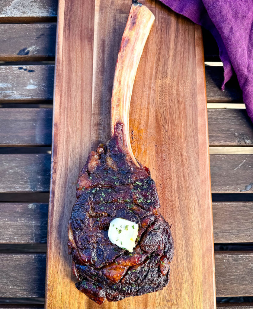 smoked tomahawk steak with butter on a platter