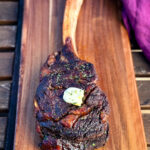 smoked tomahawk steak with butter on a platter