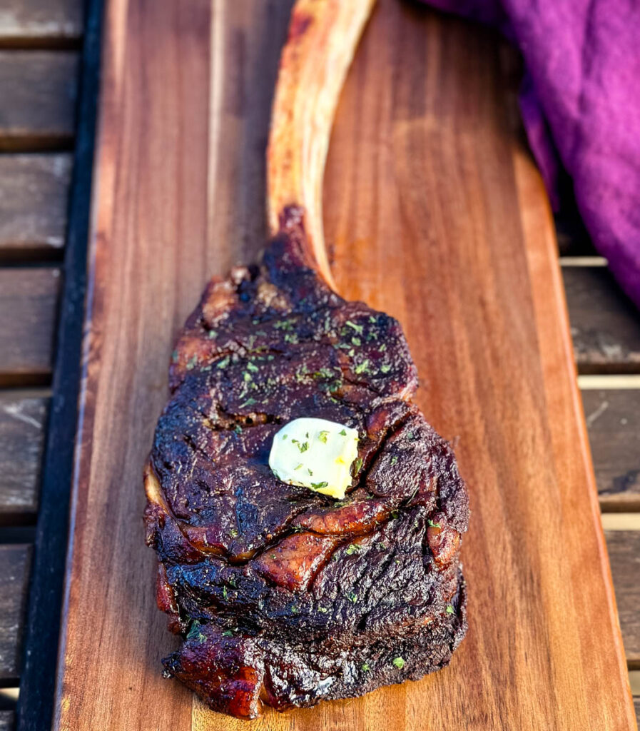 smoked tomahawk steak with butter on a platter