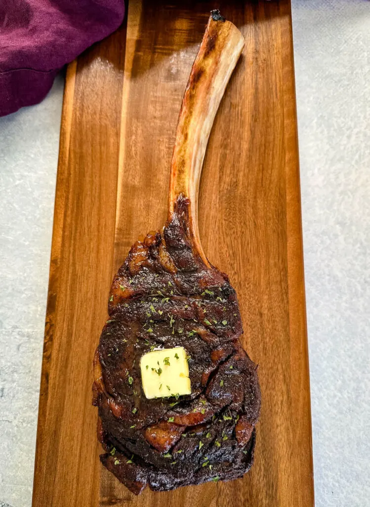 smoked tomahawk steak with butter on a platter