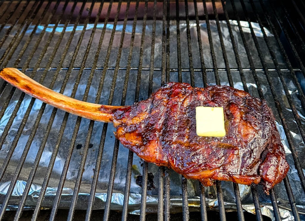 smoked tomahawk steak with butter on a Traeger pellet grill