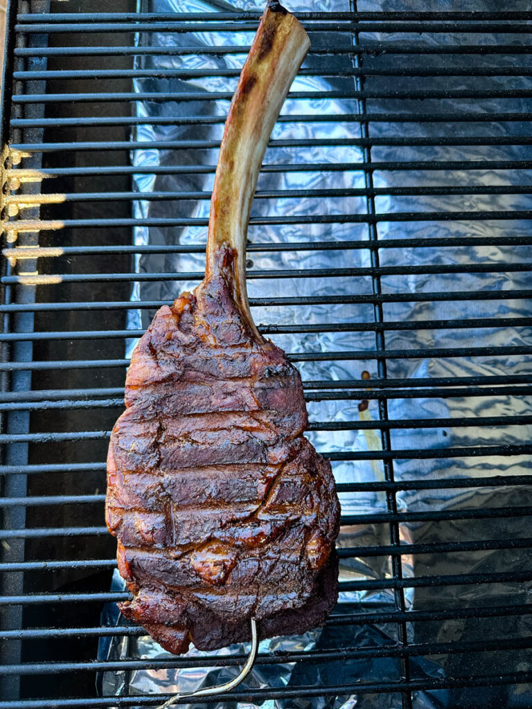 smoked tomahawk steak with butter on a Traeger pellet grill