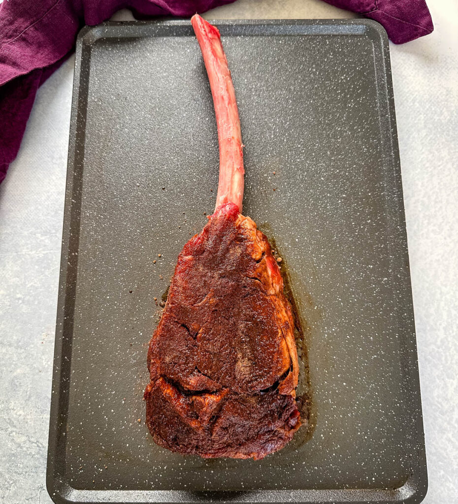 raw seasoned tomahawk steak with butter on a platter