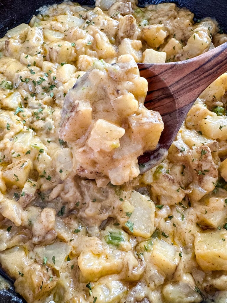 smothered potatoes with onions, peppers, and gravy in a cast iron skillet