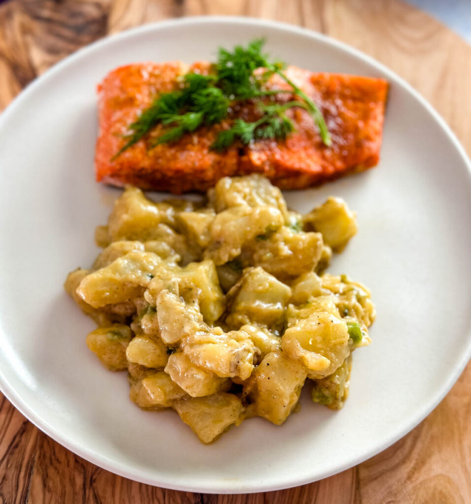 smothered potatoes on a plate with baked salmon