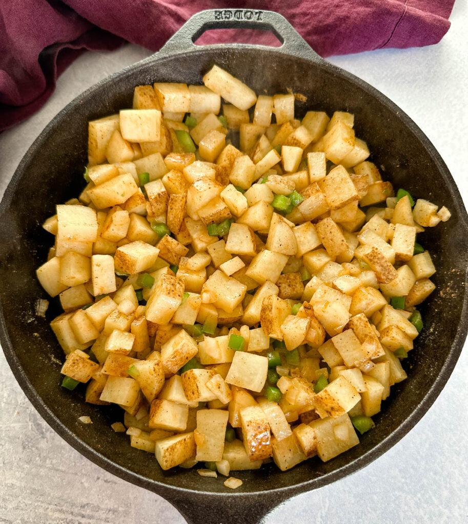 fried potatoes, onions, and peppers in a cast iron skillet