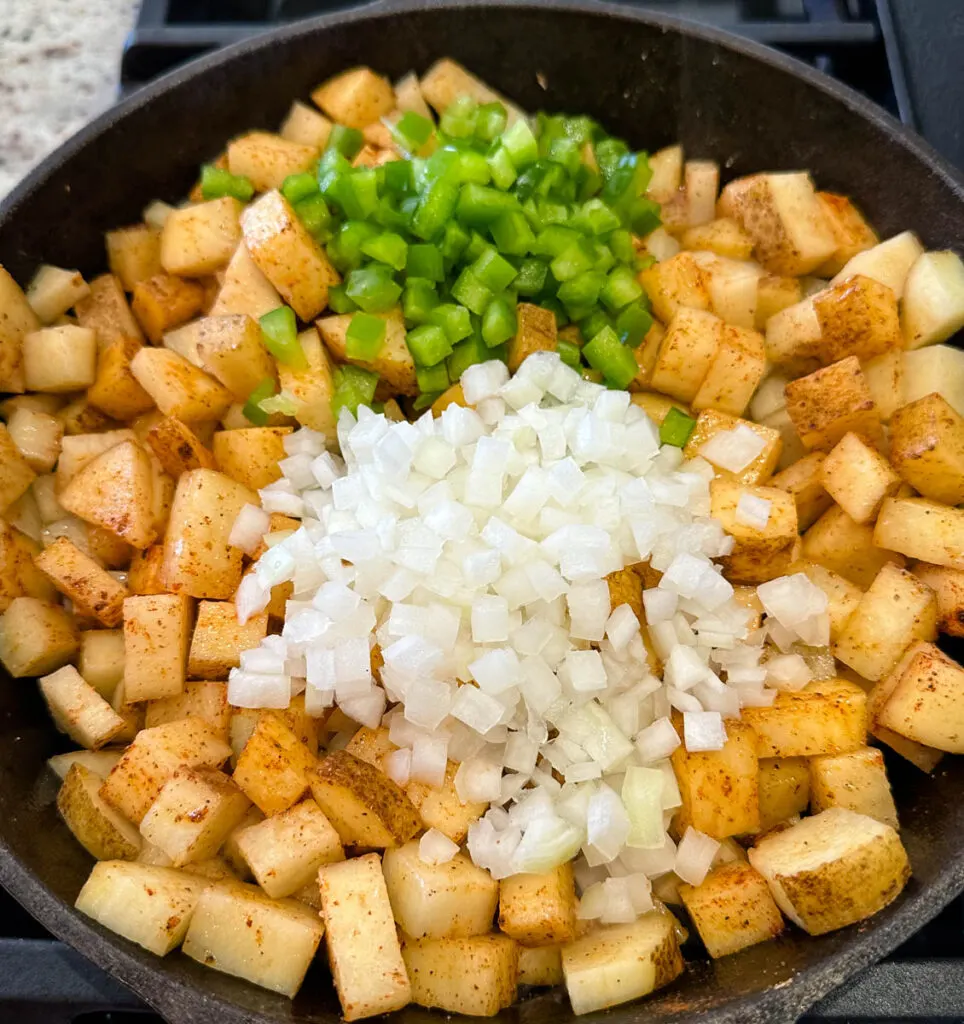 fried potatoes, onions, and peppers in a cast iron skillet