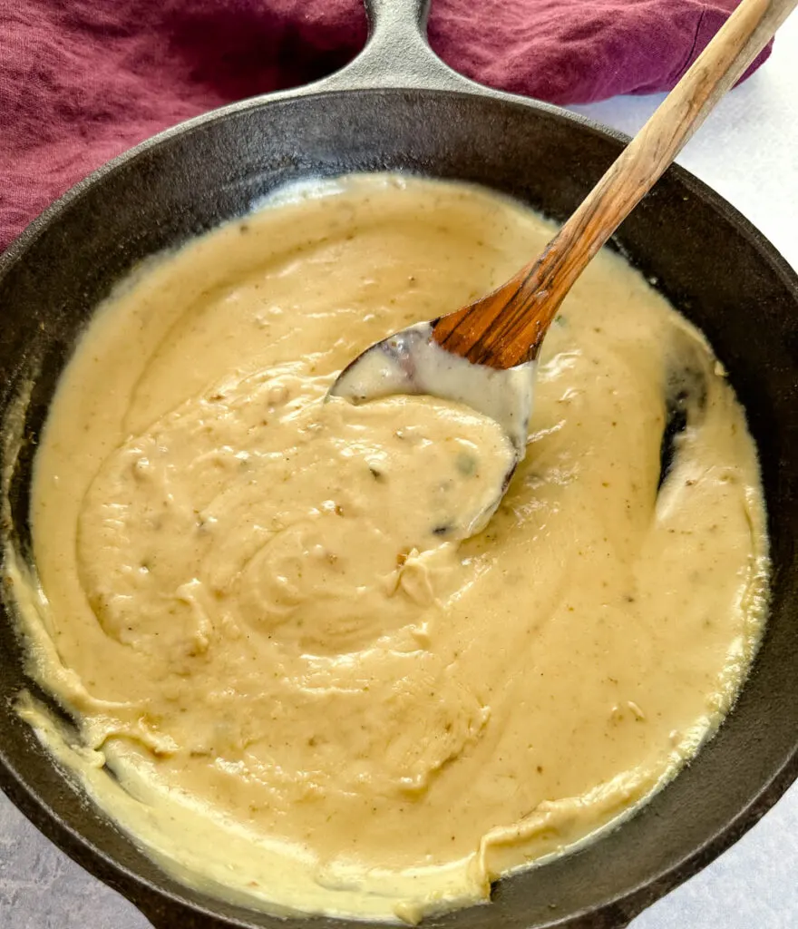 homemade gravy in a cast iron skillet with a wooden spoon
