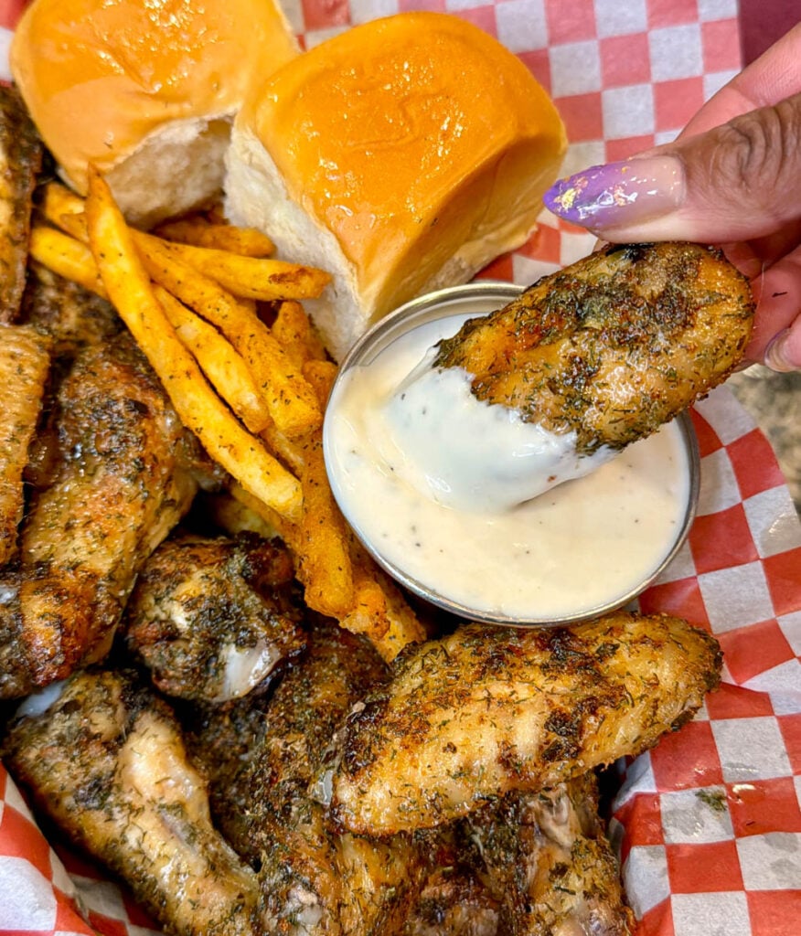 person holding ranch seasoned wing with ranch sauce