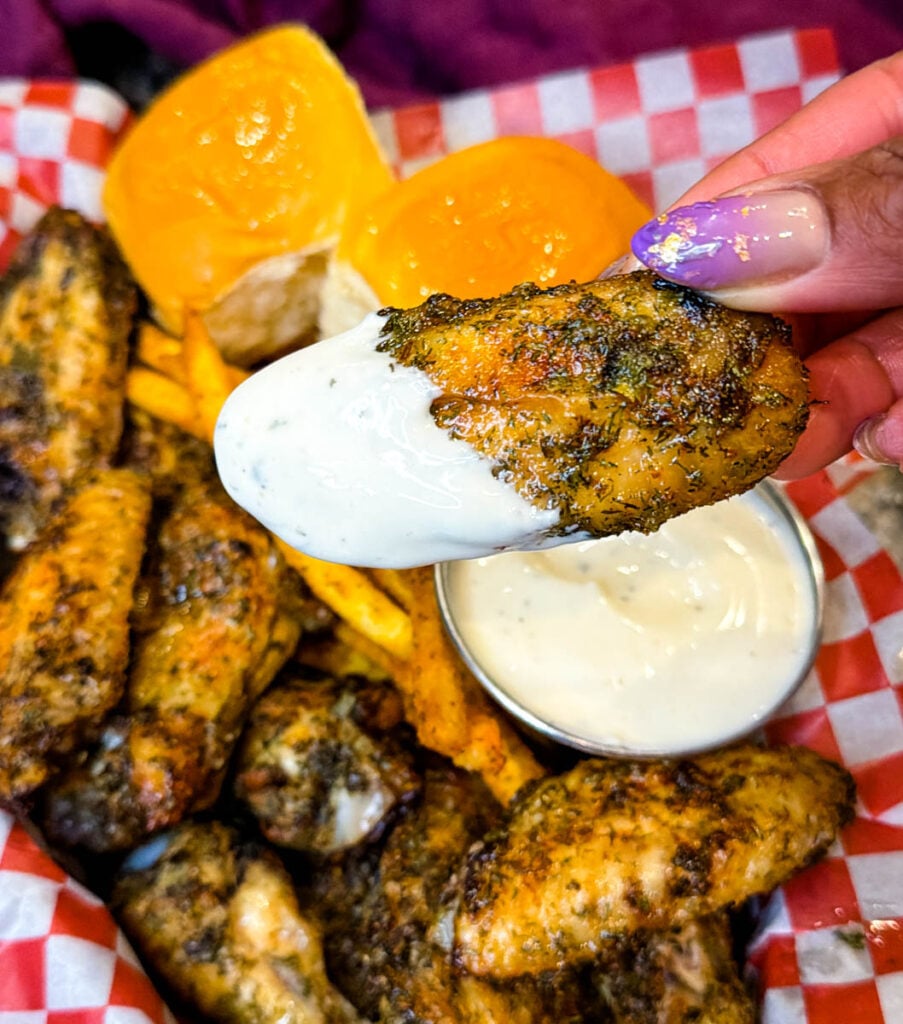 person holding ranch seasoned wing with ranch sauce