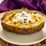 smoked baked potatoes on a plate loaded with sour cream, cheese, and bacon