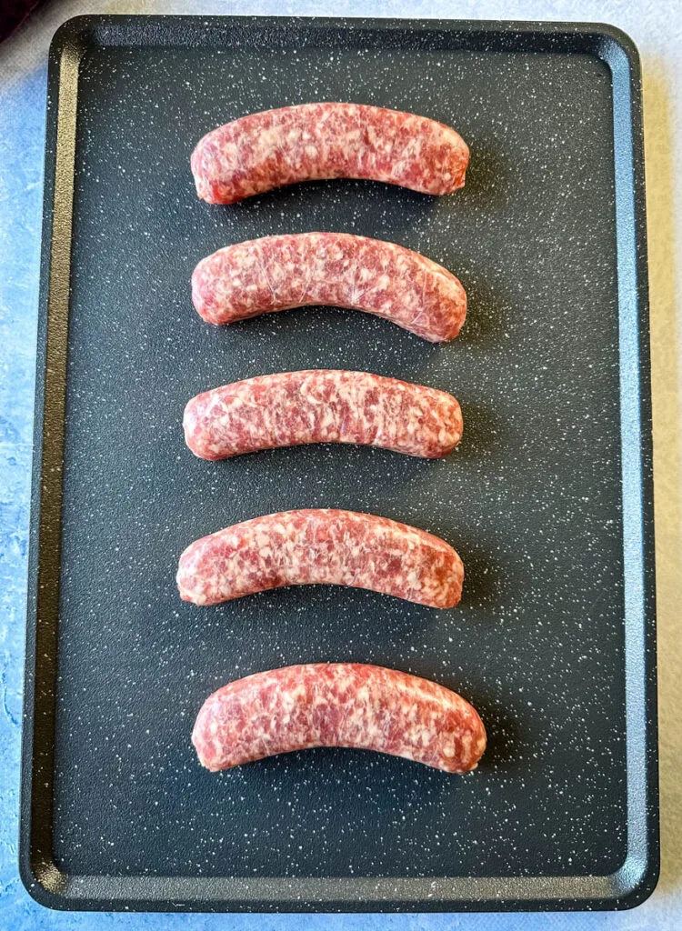 uncooked brats on a sheet pan