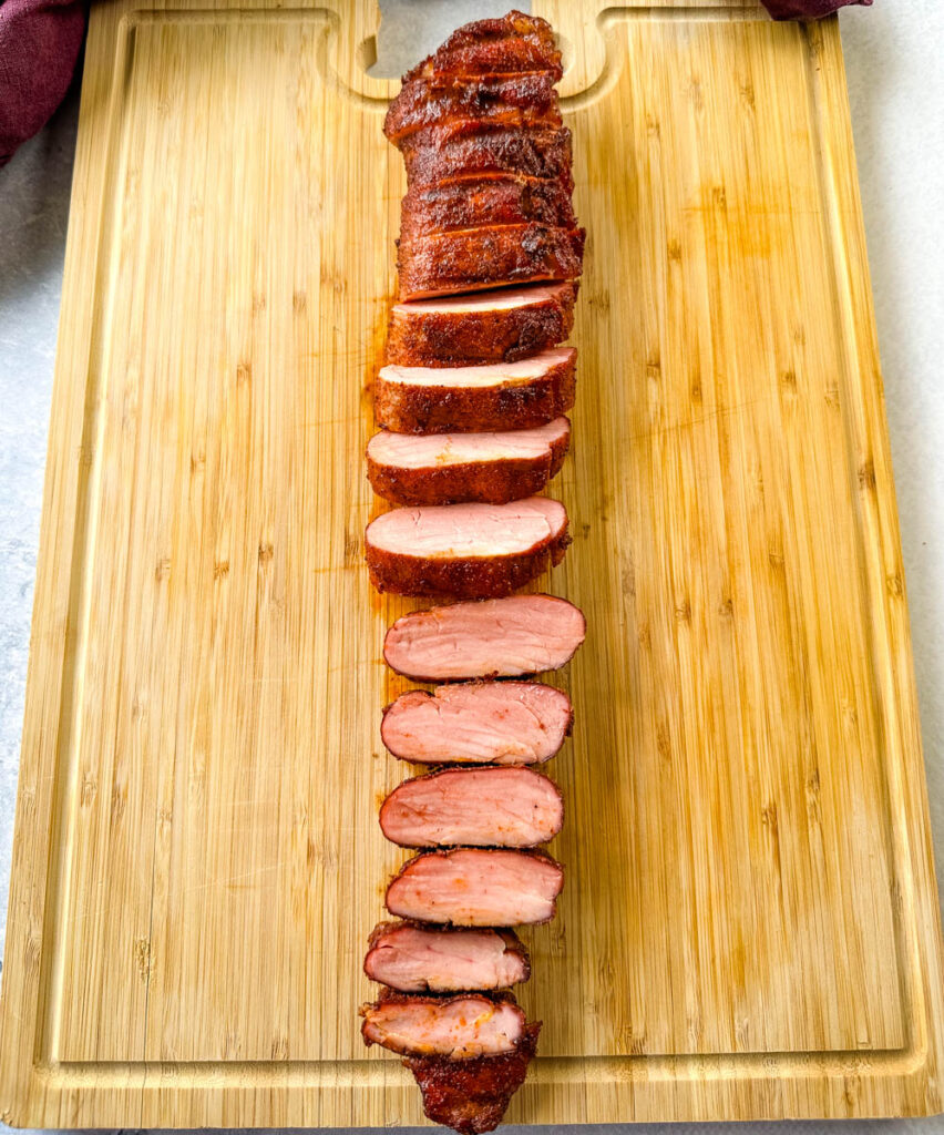 sliced smoked pork tenderloin on a wooden cutting board