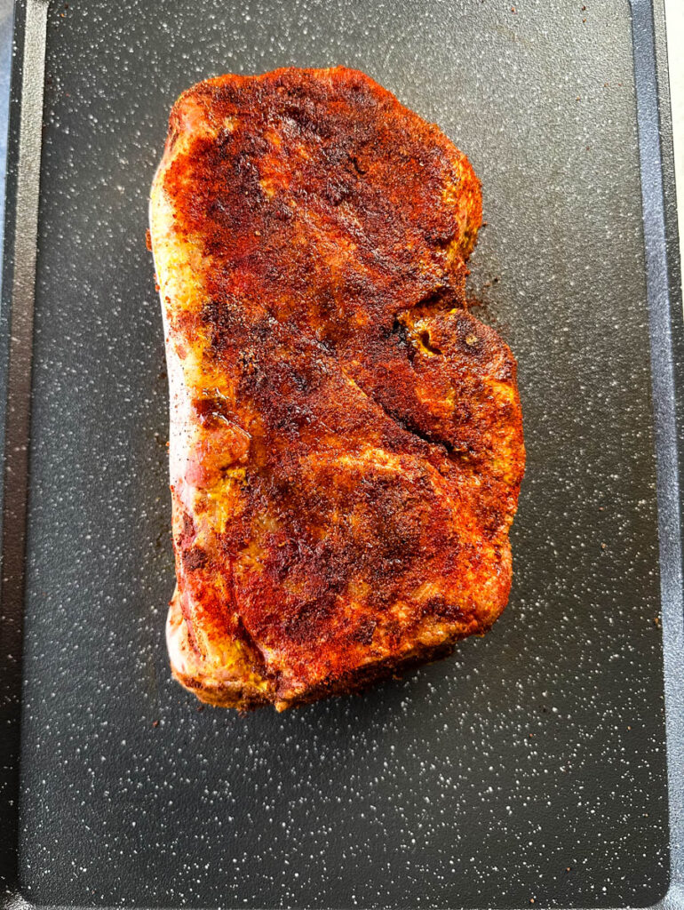 raw seasoned pork shoulder on a sheet pan