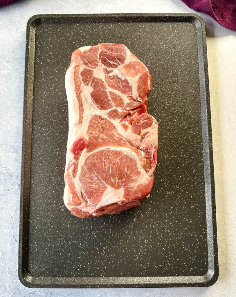 raw pork shoulder on a sheet pan