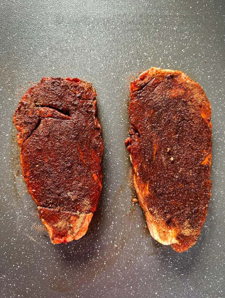 raw seasoned ribeyes on a plate