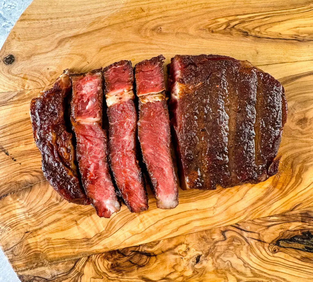 sliced smoked ribeye steak on a cutting board