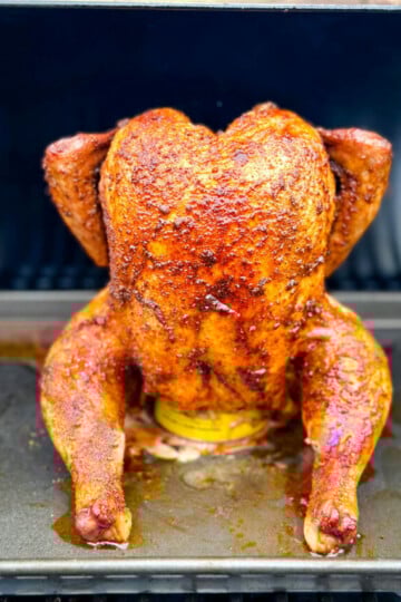 cooked, smoked seasoned whole chicken on a beer can in a Traeger smoker pellet grill