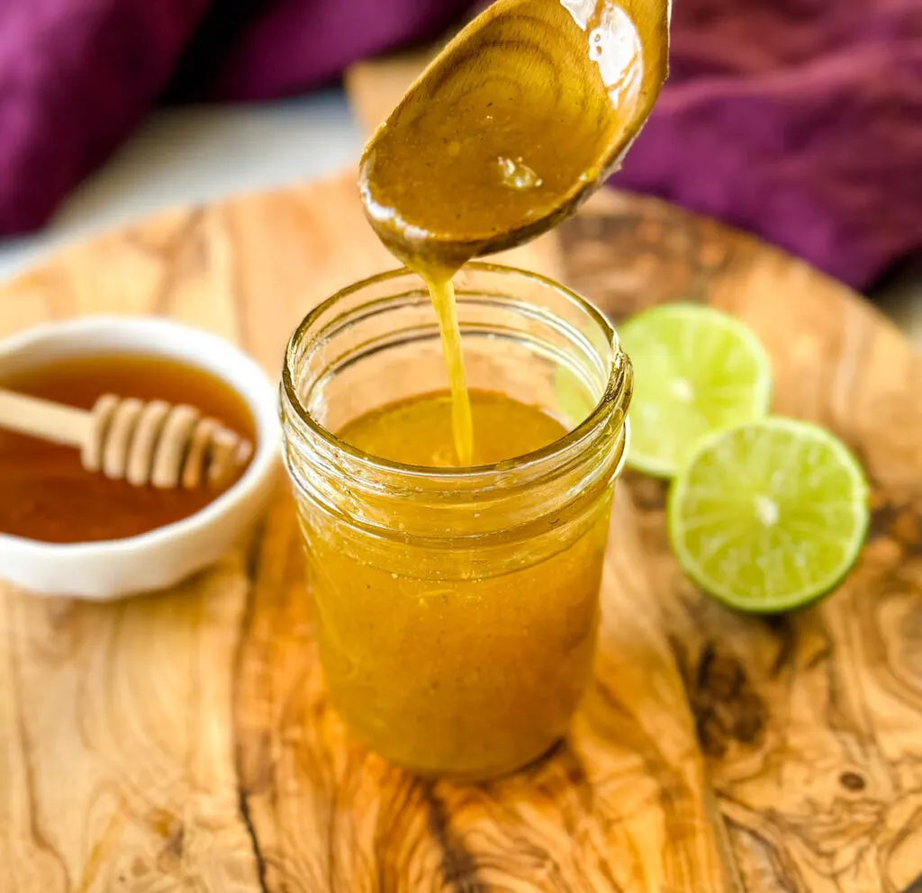 a spoonful of honey lime salad dressing over a glass jar