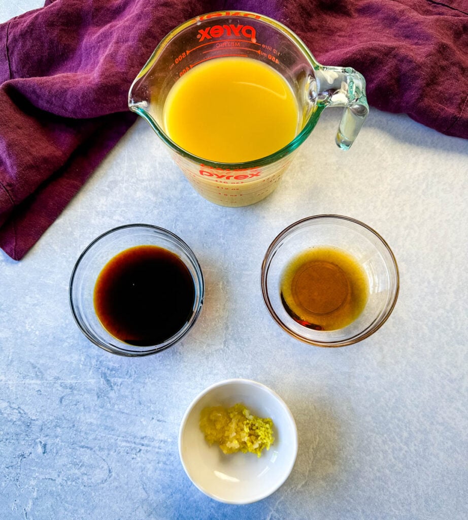 broth, soy sauce, sesame oil, ginger, and garlic in separate glass bowls
