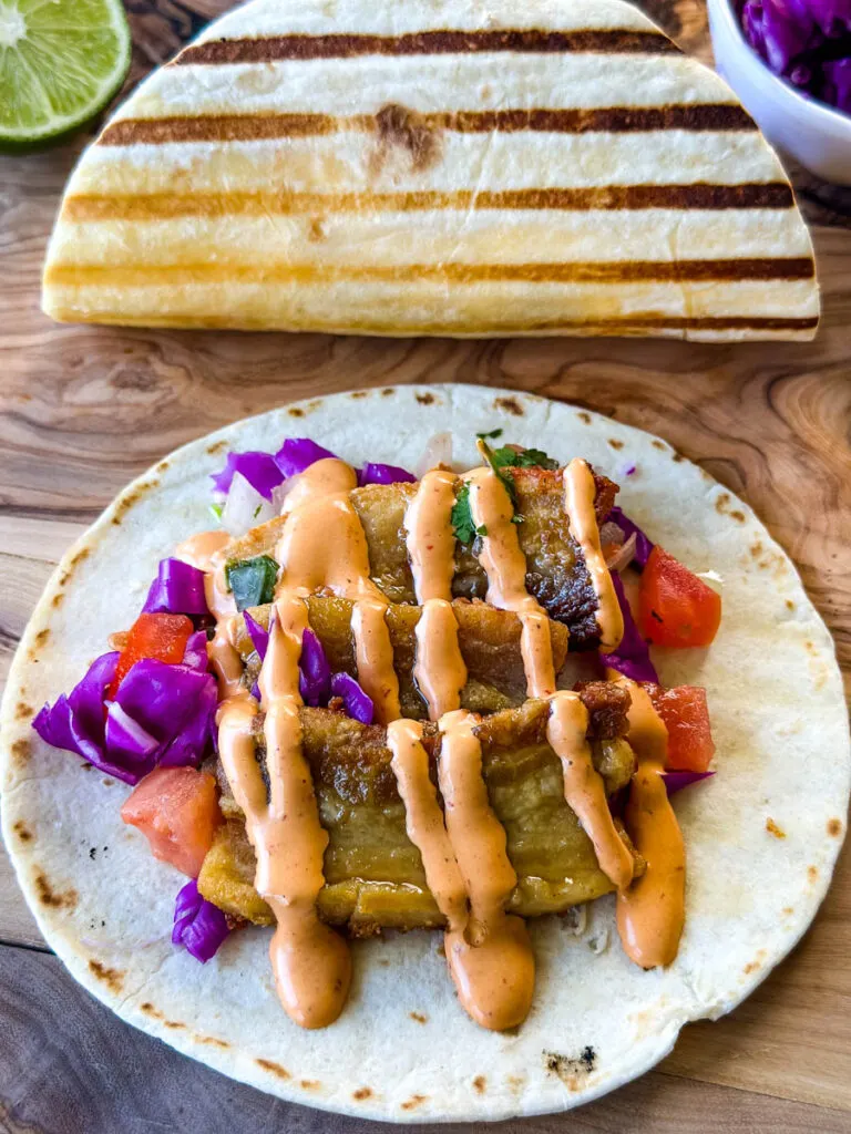 pork belly taco with seared flour tortilla and spicy Chipotle sauce and pico de gallo