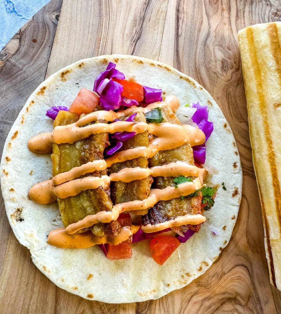 pork belly taco with seared flour tortilla and spicy Chipotle sauce and pico de gallo