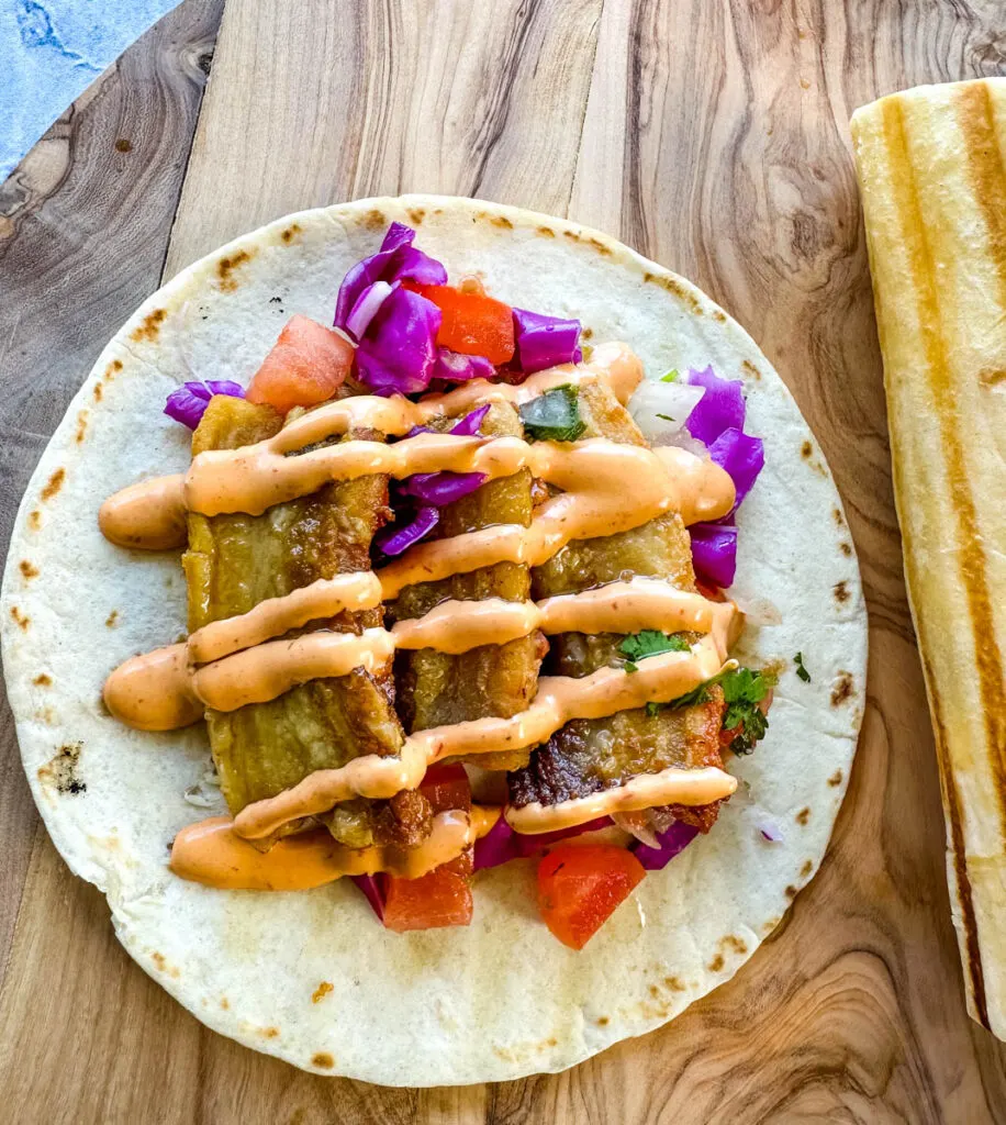 pork belly taco with seared flour tortilla and spicy Chipotle sauce and pico de gallo