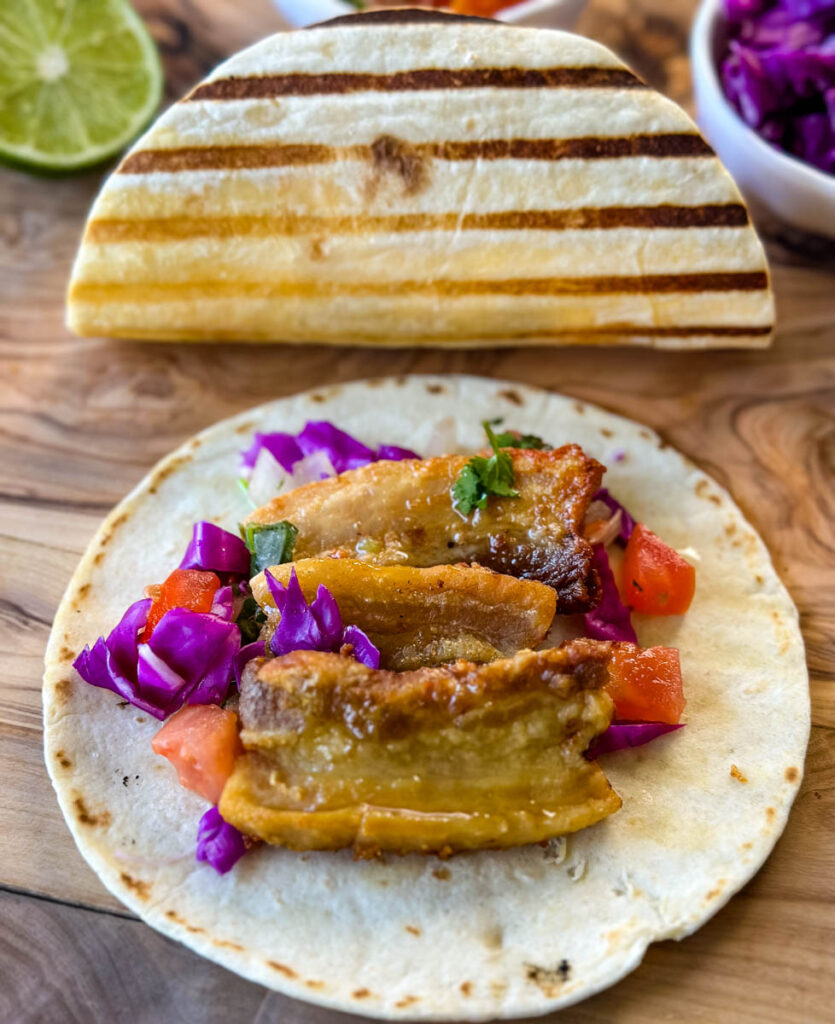 pork belly taco with seared flour tortilla and spicy Chipotle sauce and pico de gallo