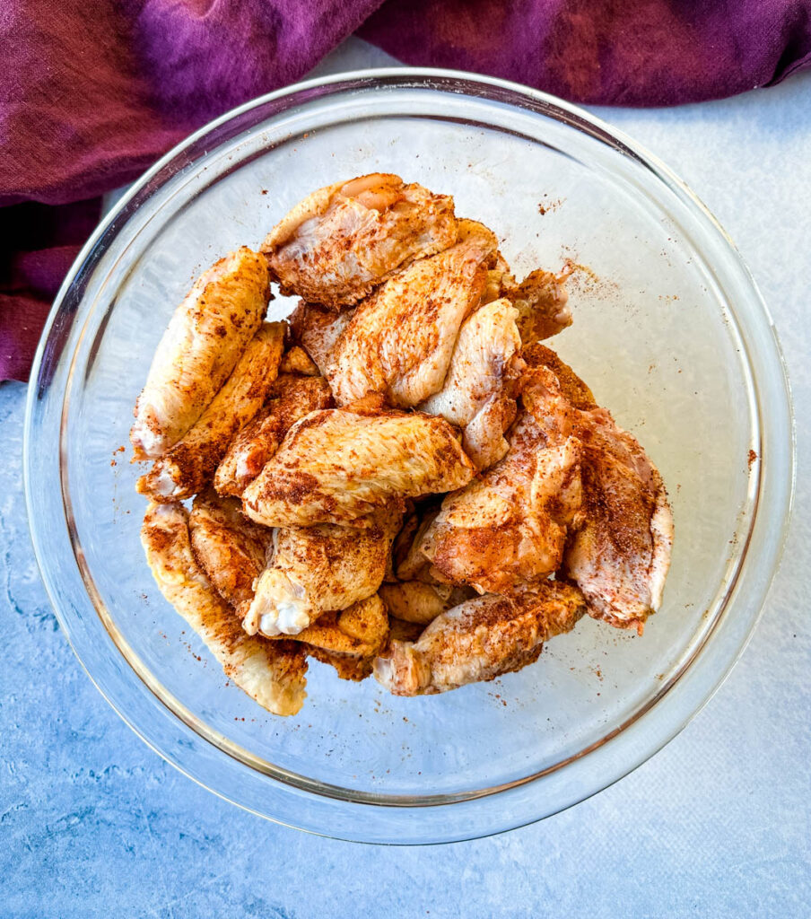 raw seasoned chicken wings in a glass bowl