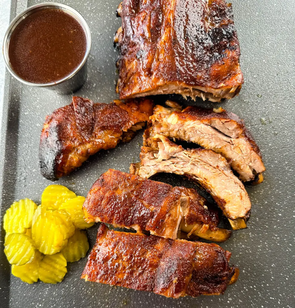 slow cooker Crockpot ribs on a flat surface with pickles and BBQ sauce