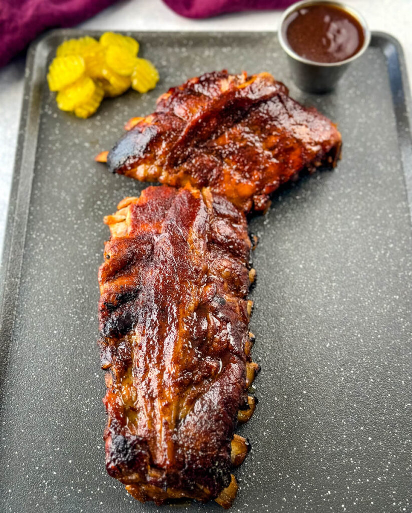 slow cooker Crockpot ribs on a flat surface with pickles and BBQ sauce