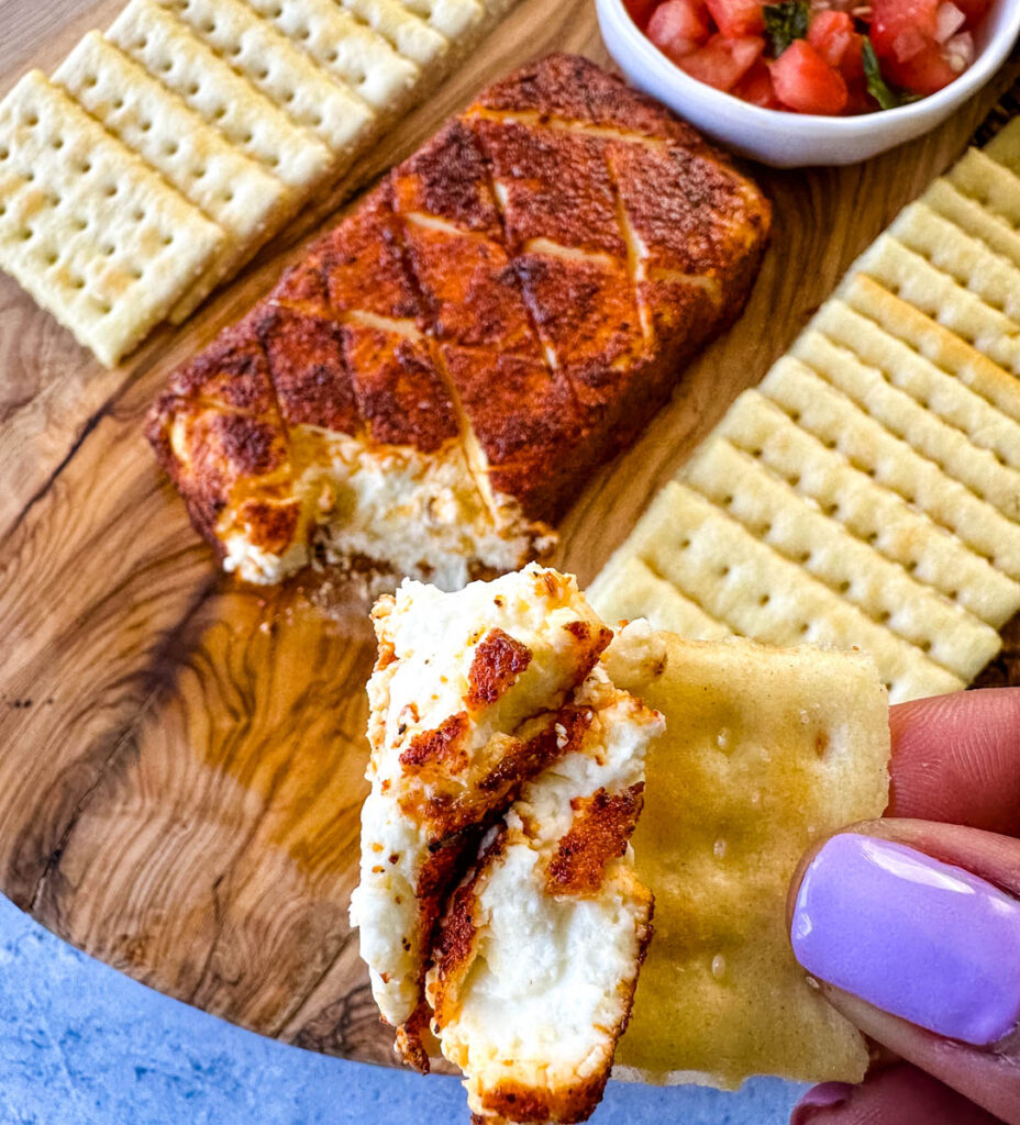 person holding smoked cream cheese on a club cracker