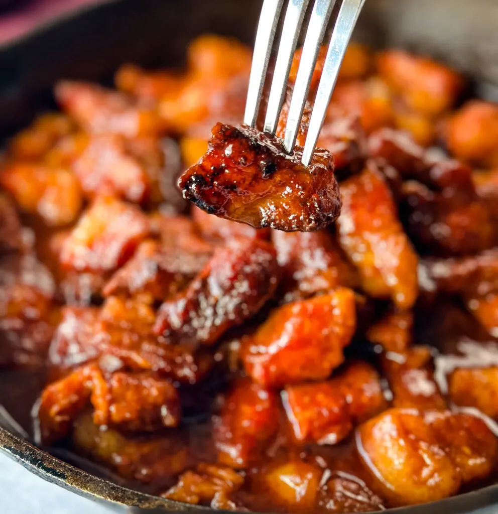 Traeger smoked pork belly burnt end with BBQ sauce held by a fork