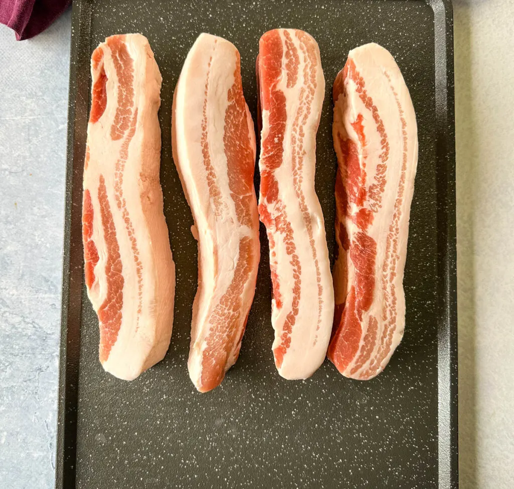 raw pork belly strips on a sheet pan