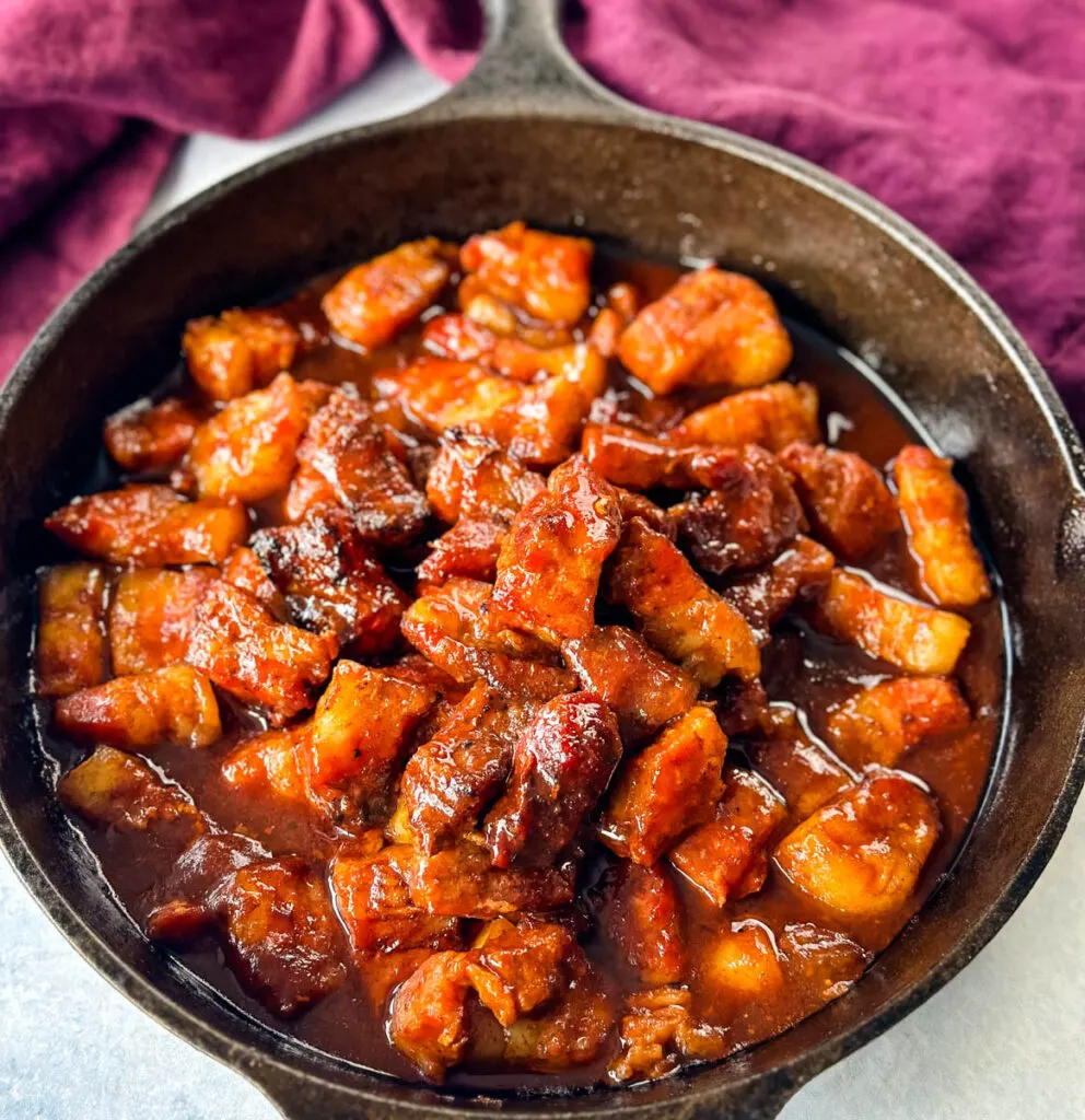 Traeger smoked pork belly burnt end with BBQ sauce in a cast iron skillet