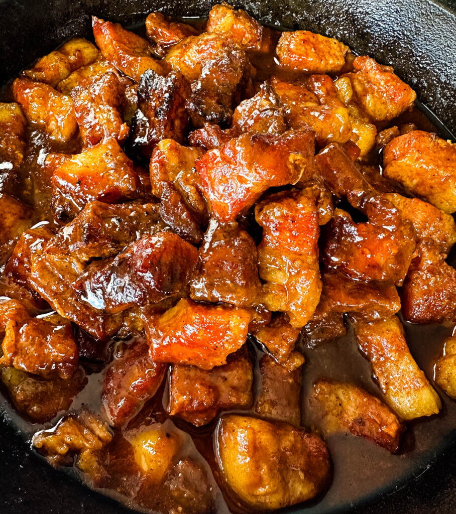 Traeger smoked pork belly burnt end with BBQ sauce in a cast iron skillet