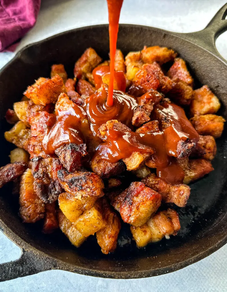 smoked pork belly in a cast iron skillet drizzled with BBQ sauce