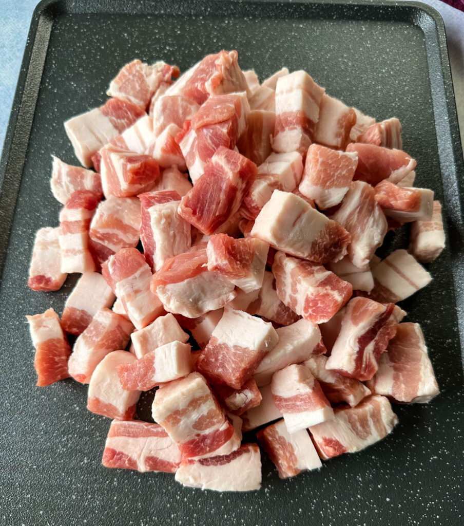 raw pork belly cut into chunks on a sheet pan