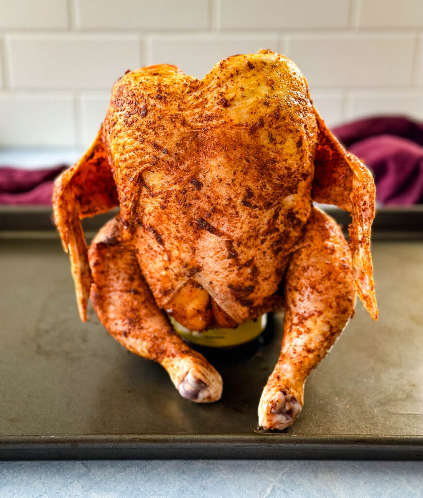 raw seasoned whole chicken on top of a beer can