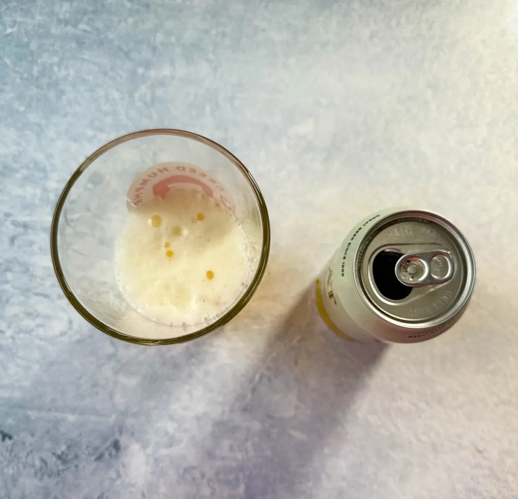 an open can of beer and a half glass of beer