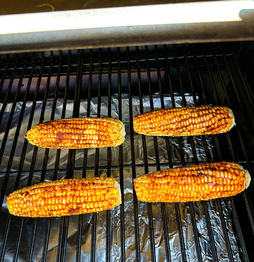 fresh corn on the cob ears with smoked garlic butter and spices on a Traeger smoker pellet grill