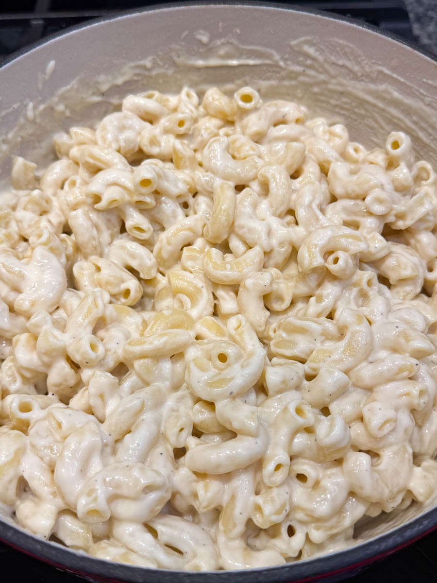 Close-up of creamy stovetop mac and cheese in a large pot, elbow macaroni coated in smooth white cheese sauce.