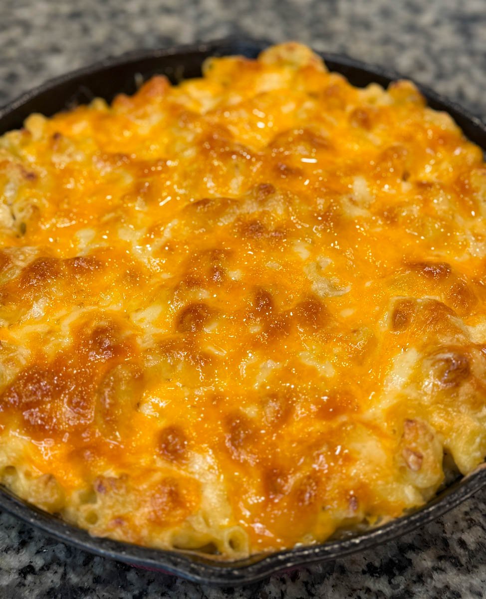 Golden, bubbly Southern baked mac and cheese in a skillet on a countertop, cheese melted evenly across the top.