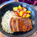 blackened chicken breasts with rice and mango salsa in a black bowl