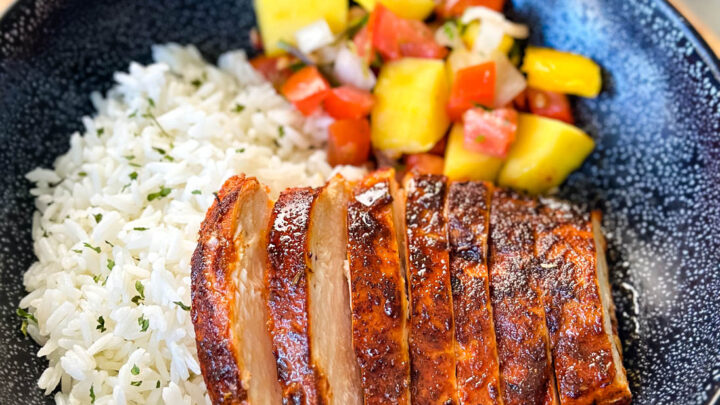 blackened chicken breasts with rice and mango salsa in a black bowl