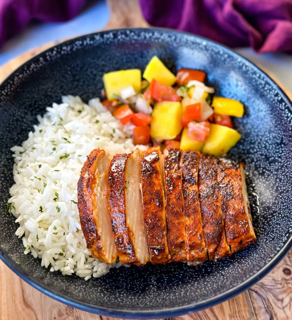 blackened chicken breasts with rice and mango salsa in a black bowl