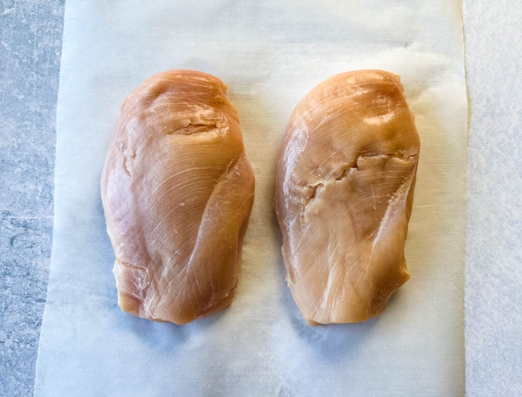raw chicken breasts on parchment paper